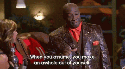 a man in a suit is talking to a woman and says " when you assume "