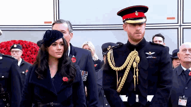 a man and a woman in military uniforms are standing next to each other in a crowd .