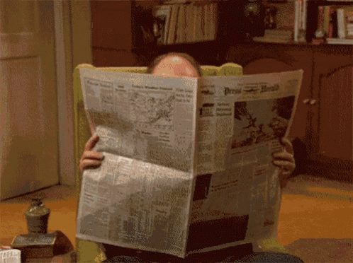 a man sitting in a chair reading the press herald