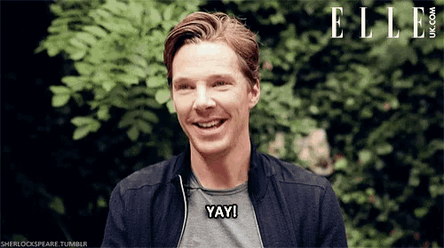 a man in a black jacket is smiling and saying yay