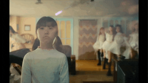 a girl is standing in front of a mirror with a group of girls in the background