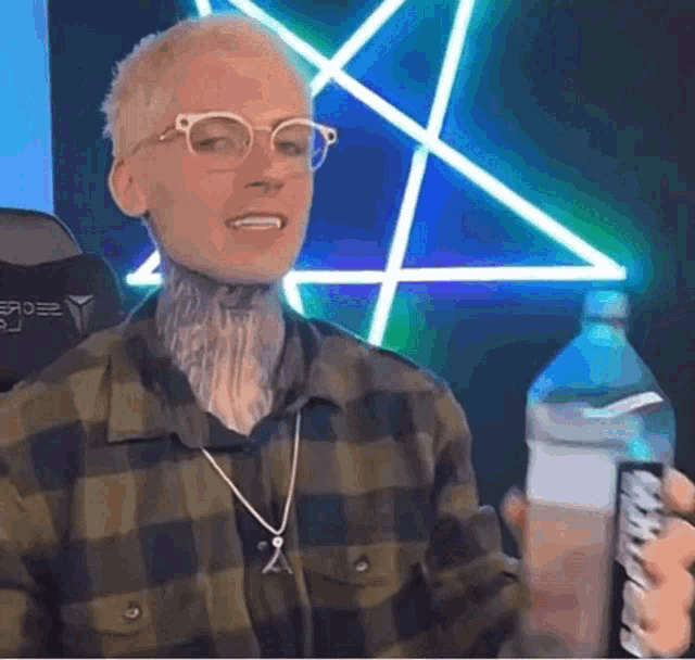 a man in a plaid shirt is holding a bottle of water .