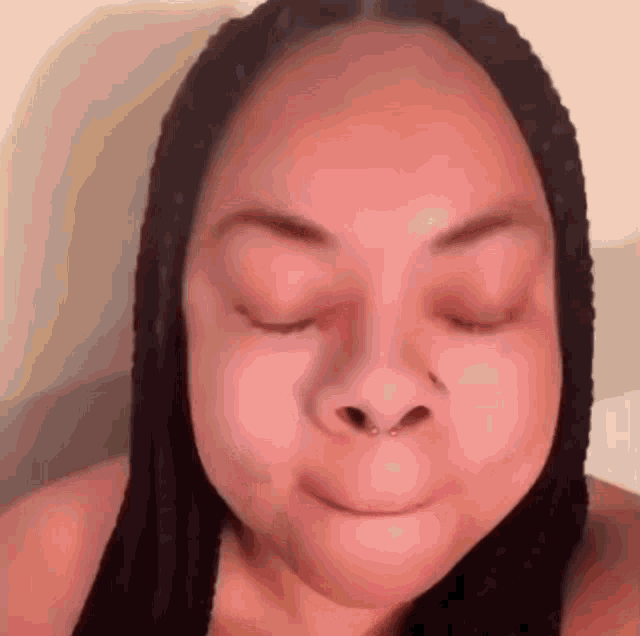 a close up of a woman 's face with her eyes closed and a nose ring .