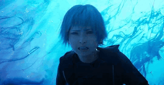 a woman with blue hair is swimming in the ocean and looking at the camera .