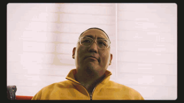 a man with glasses and a yellow jacket looks up