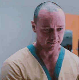 a close up of a man with a shaved head wearing a scrub top and a blue collar .