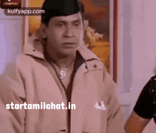 a man wearing a hat and a jacket is standing in front of a wall with the words starttamilchat.in on the bottom