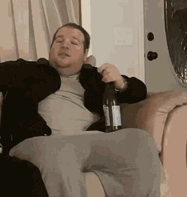 a man is sitting on a couch holding a bottle of water
