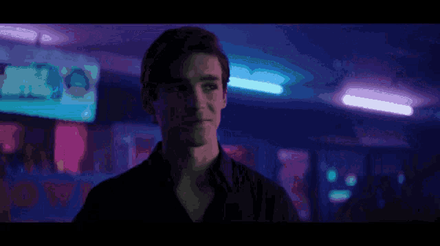 a man is standing in a dark room with purple lights