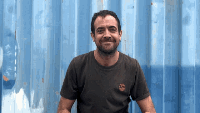 a man wearing a t-shirt with a circle on the front smiles