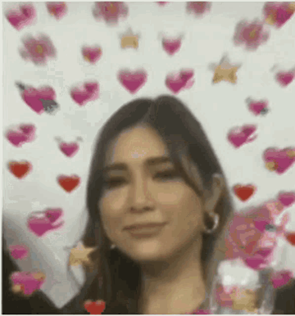 a woman is standing in front of a wall with hearts and stars .