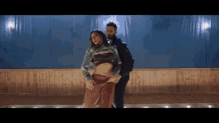 a man is holding a woman 's waist while they dance in a room .