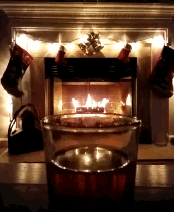 a fireplace with christmas stockings and a glass of wine