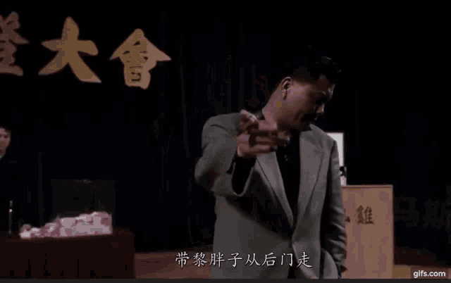 a man in a suit stands in front of a podium that says gifs.com on it