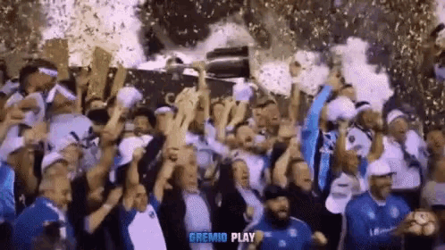 a group of people holding up a trophy with the word gremio play on the bottom right