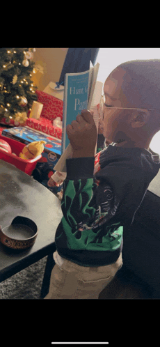 a little boy wearing glasses is reading a book called home is paradise
