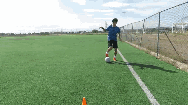 a boy in a blue shirt kicking a soccer ball