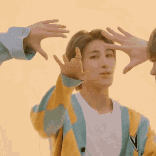 a man is making a heart shape with his hands while another man holds his hands over his head .