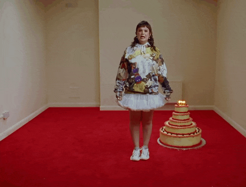 a woman in a hoodie stands in front of a cake with candles on it