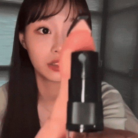 a woman is holding a bottle of lipstick in her hand and looking at it .