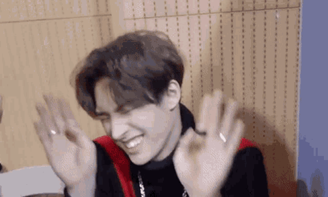 a young man is laughing and making a funny face with his hands in the air .