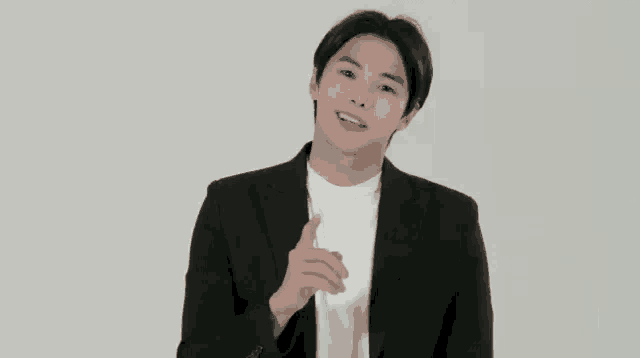 a young man in a black suit and white shirt is talking