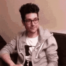 a man wearing glasses is sitting on a couch .