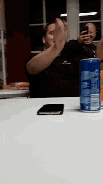 a can of pepsi sits on a table next to a man taking a picture of himself