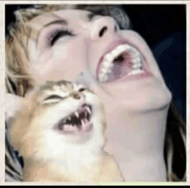 a woman is laughing while holding a cat in her lap