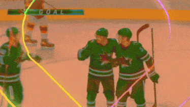 three hockey players celebrate a goal in front of a goalie