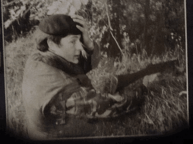 a black and white photo of a man in a beret holding a gun