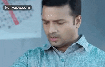 a man in a blue shirt is making a funny face and looking down .
