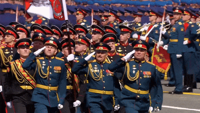 a group of men in military uniforms salute while holding a flag with the letter c on it