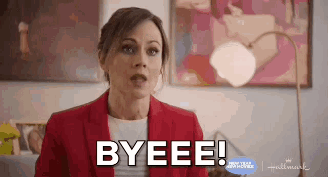 a woman in a red suit is saying byeee while sitting in a living room .