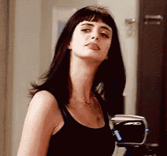 a woman wearing a black tank top is sticking her tongue out .