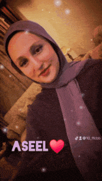 a woman wearing a purple scarf with the name aseel written on the bottom