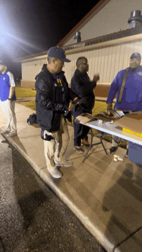 a group of men standing around a table with one man wearing a blue jacket with the word eagles on it