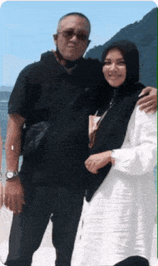 a man and a woman are posing for a picture on the beach