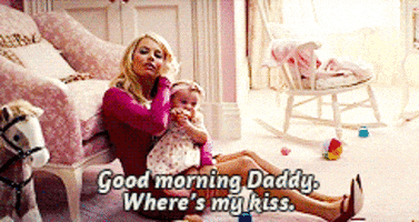 a woman is sitting on the floor with a baby and says good morning daddy where 's my kiss