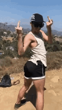 a man in a tank top and shorts is giving the middle finger