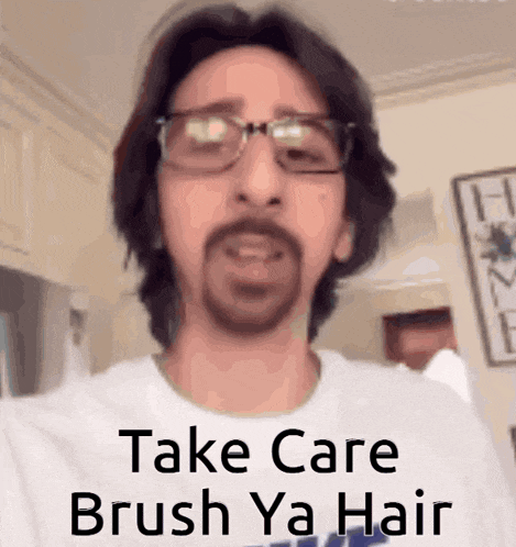 a man with glasses and a beard is wearing a white shirt that says " take care brush ya hair "