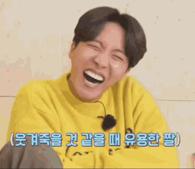 a man in a yellow sweater is laughing with his mouth open in a foreign language .