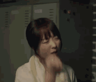 a woman is standing in a locker room with a towel around her neck and the words `` fighting '' written next to her .
