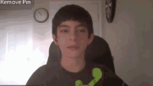 a boy is sitting in front of a clock and a screen that says " remove pin "