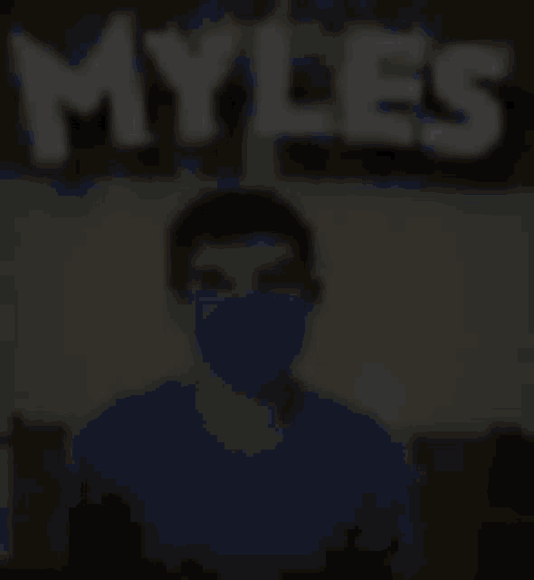 a blurry picture of a person wearing a mask with the word myles behind them