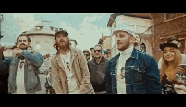 a group of men are standing next to each other on a street in front of a crowd of people .