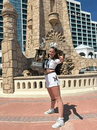 a cheerleader holding a trophy in front of a building