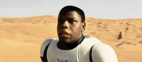 a man in a storm trooper costume is standing in the middle of a desert .