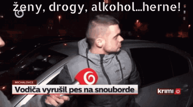 a man talking into a microphone in front of a car that says vodyca vyrusil pes na snouborde on it