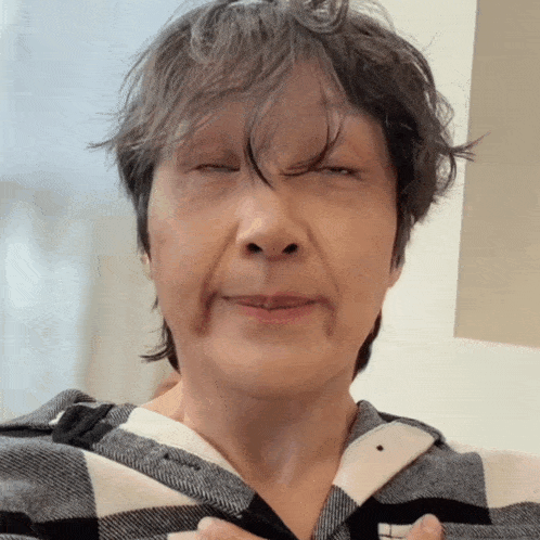 a close up of a woman 's face with her eyes closed and a plaid shirt on